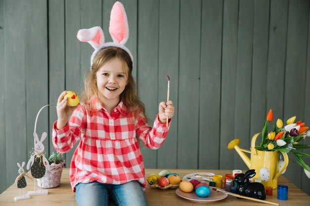 Meisje in konijntjesoren die ei schilderen voor Pasen