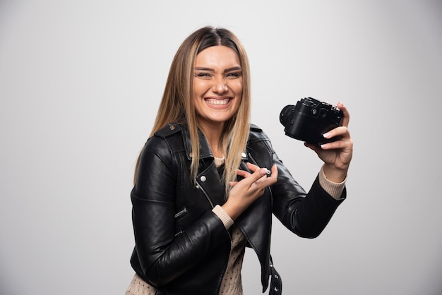 Meisje in leren jas die haar fotogeschiedenis op de camera controleert.