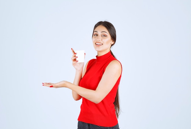 Meisje in rood shirt met een koffiekopje en ruiken.