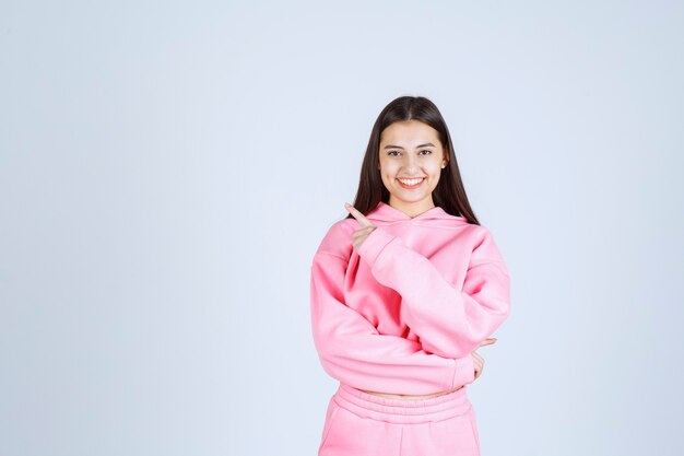 Meisje in roze pyjama naar links wijzend