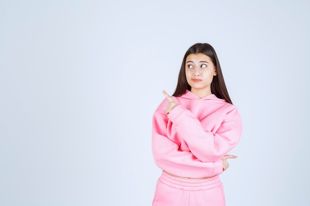 Meisje in roze pyjama naar links wijzend