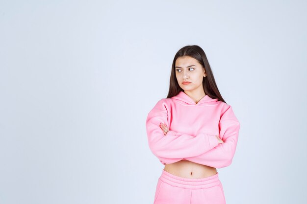 Meisje in roze pyjama's die de armen kruisen en ziet er agressief uit.