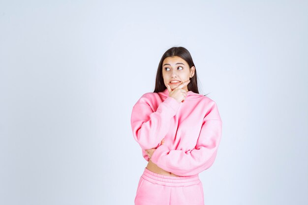 Meisje in roze pyjama's die positieve en vervelende houdingen geven