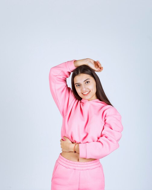 Meisje in roze pyjama's die vrolijke en verleidelijke poses geven