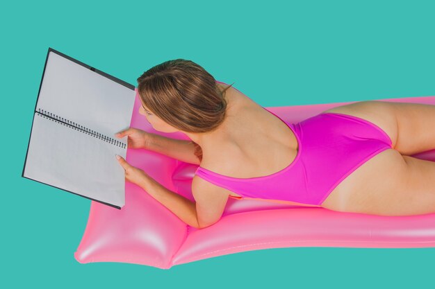 Meisje in zwembroek met folder op pool matras