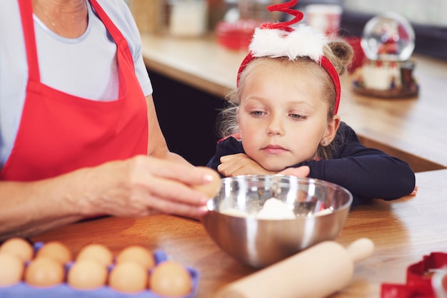 Meisje kijken naar grootmoeder die een cake maakt