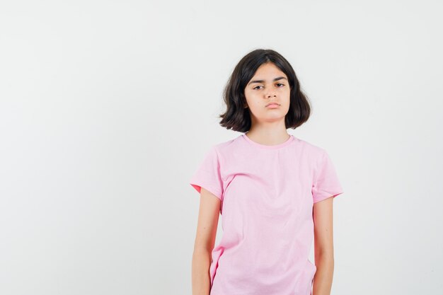 Meisje kijkt naar voorzijde in roze t-shirt en kijkt somber. vooraanzicht.