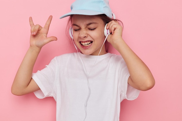 Meisje kind in koptelefoon poseren op een roze achtergrond