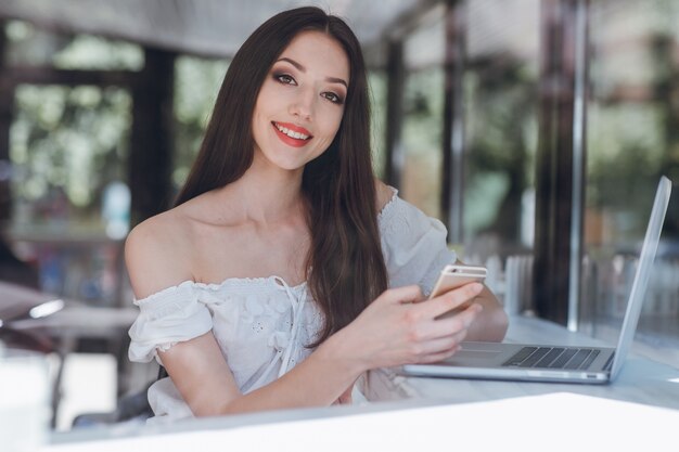 Meisje lacht met rood geschilderde lippen met een mobiel in de hand