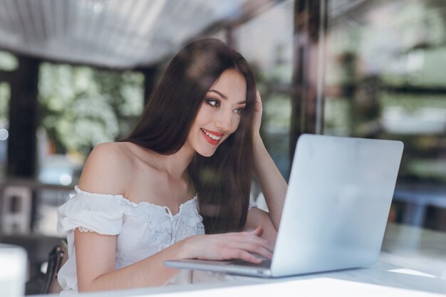 Meisje lacht met rood geverfde lippen te typen op een laptop