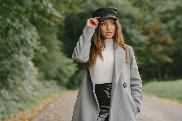 Meisje loopt. Vrouw in een grijze jas. Brunette met een zwarte pet.