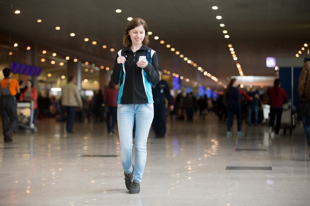 Meisje met behulp van mobiele telefoon in de luchthaven