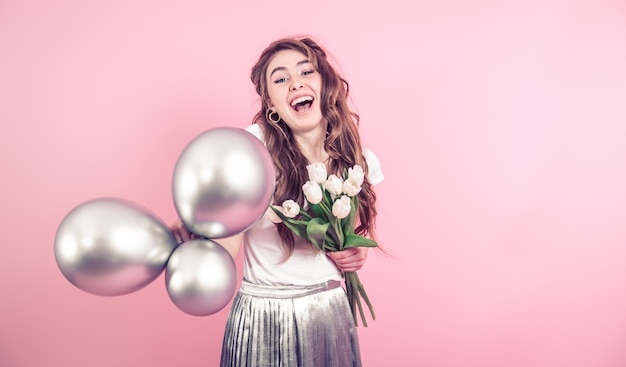 Meisje met bloemen en ballonnen op een gekleurde muur