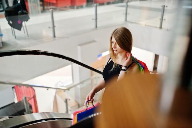 Meisje met boodschappentassen in het winkelcentrum op de roltrap