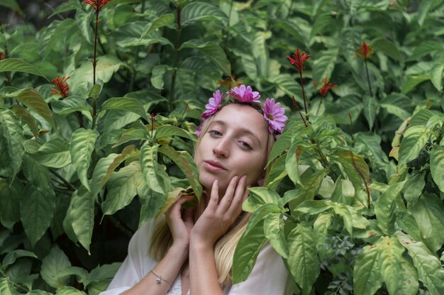 Meisje met de handen op het gezicht en omringd door planten