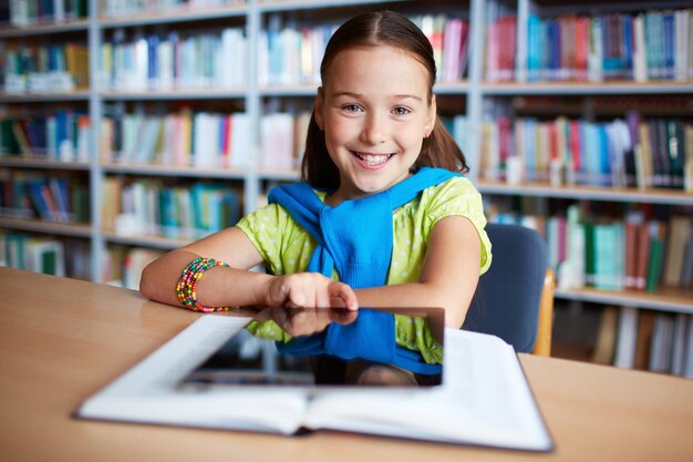 Meisje met digitale tablet in de bibliotheek