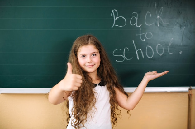 Gratis foto meisje met duim omhoog op schoolbord