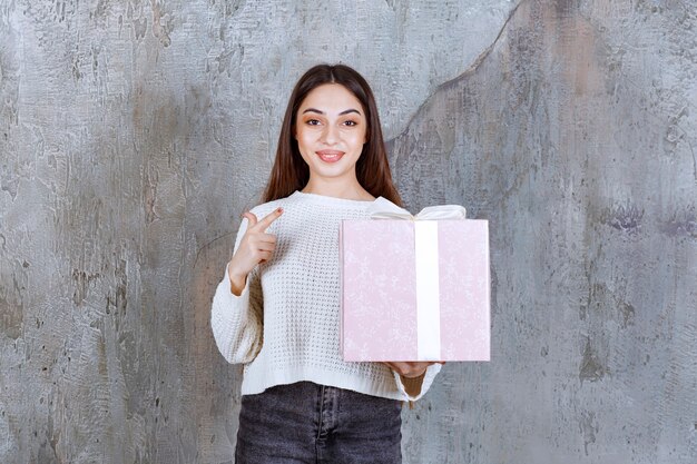 Meisje met een paarse geschenkdoos omwikkeld met een wit lint.