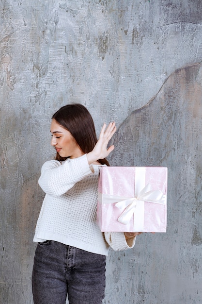 Meisje met een paarse geschenkdoos omwikkeld met wit lint en iets stoppen.