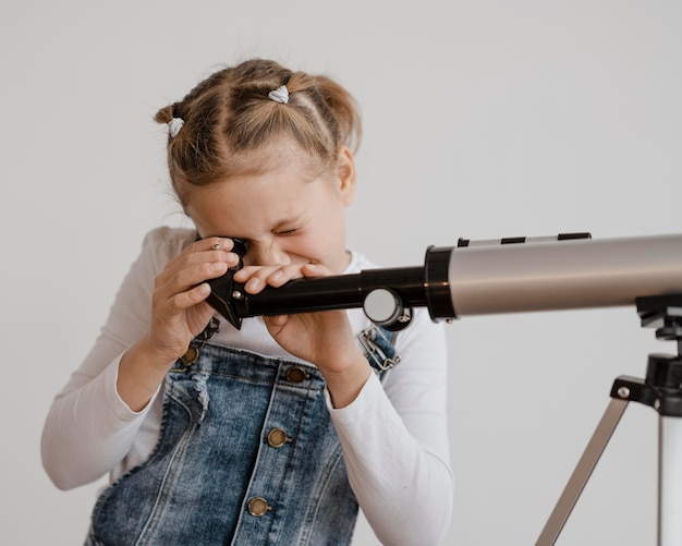 Gratis foto meisje met een telescoop in de klas