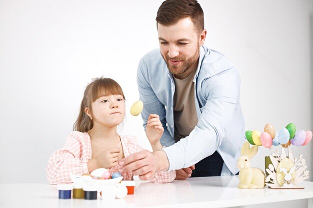 Meisje met het syndroom van Down en haar vader spelen met gekleurde paaseieren