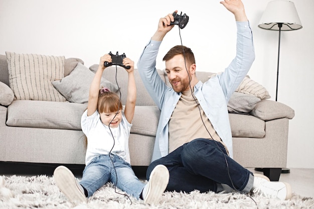 Meisje met het syndroom van Down en haar vader zitten op een vloer en spelen PlayStation