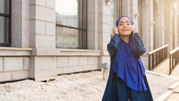 Meisje met hijab luisteren naar muziek via koptelefoon met kopie ruimte