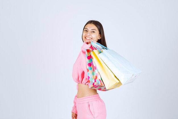 Meisje met kleurrijke boodschappentassen terug op haar schouder.