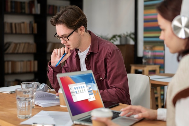 Meisje met koptelefoon met laptop samen met haar klasgenoten tijdens groepsstudie