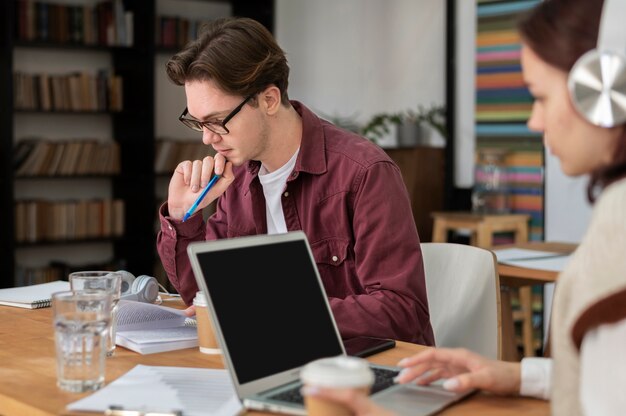 Meisje met koptelefoon met laptop samen met haar klasgenoten tijdens groepsstudie