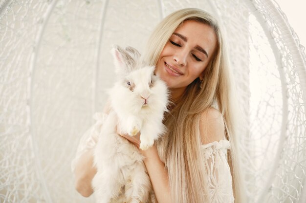 Meisje met lang blond haar met een wit konijn in haar armen.