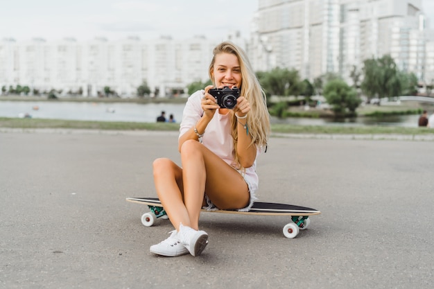 meisje met lang haar met skateboard fotograferen op camera. straat, actieve sporten