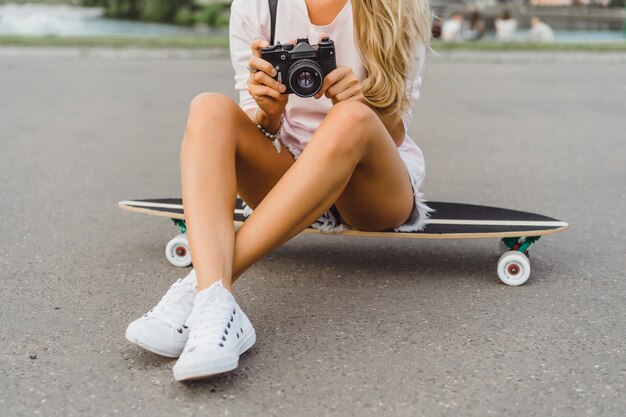 meisje met lang haar met skateboard fotograferen op camera. straat, actieve sporten