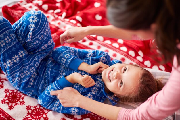 Meisje met moeder samenspelen in het bed