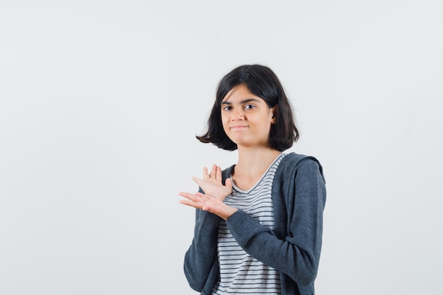 Meisje met open handpalmen in t-shirt, jasje en op zoek naar vertrouwen