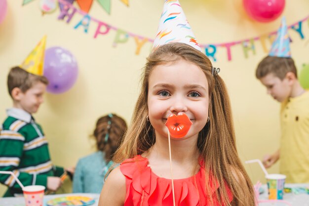 Meisje met papieren lippen op verjaardagsfeestje