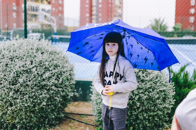 Meisje met paraplu dichtbij struiken