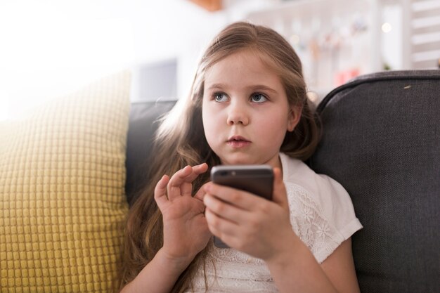 Meisje met smartphone op de bank