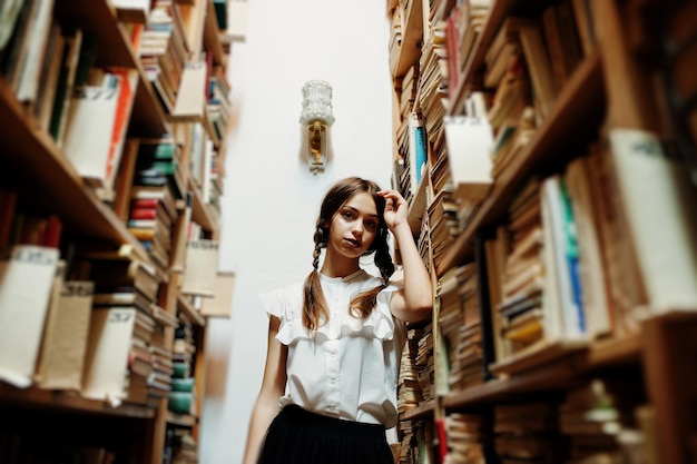 Gratis foto meisje met staartjes in witte blouse bij oude bibliotheek