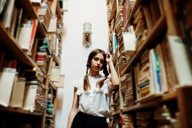 Meisje met staartjes in witte blouse bij oude bibliotheek
