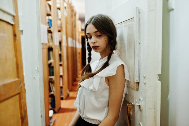 Meisje met staartjes in witte blouse bij oude bibliotheek