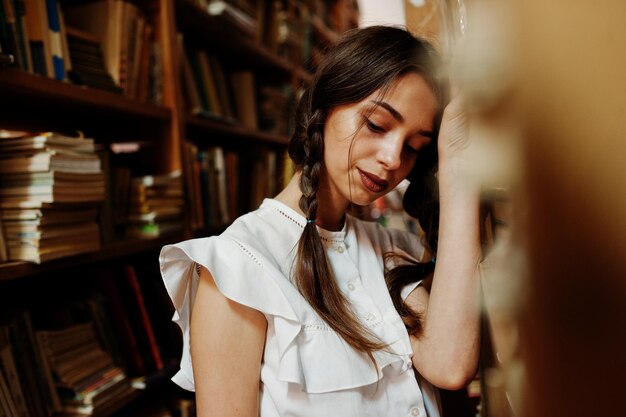 Meisje met staartjes in witte blouse bij oude bibliotheek