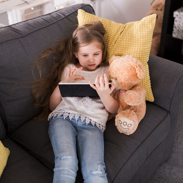 Meisje met tablet en teddy