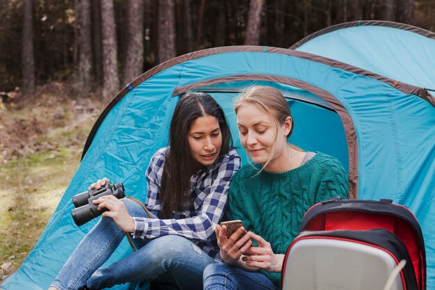 Meisje met verrekijkers en kijken naar haar vriend mobiele telefoon