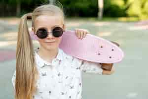 Gratis foto meisje met zonnebril en roze skateboard