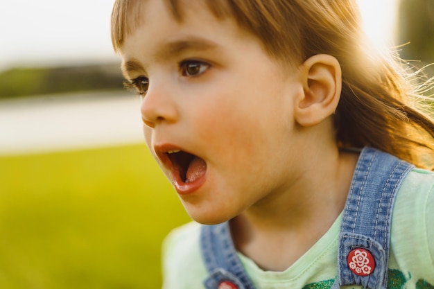 Gratis foto meisje op een paardebloemgebied, bij zonsondergang, emotioneel gelukkig kind.