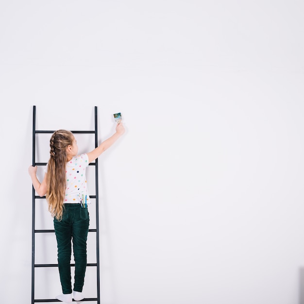 Meisje op ladder muur schilderen