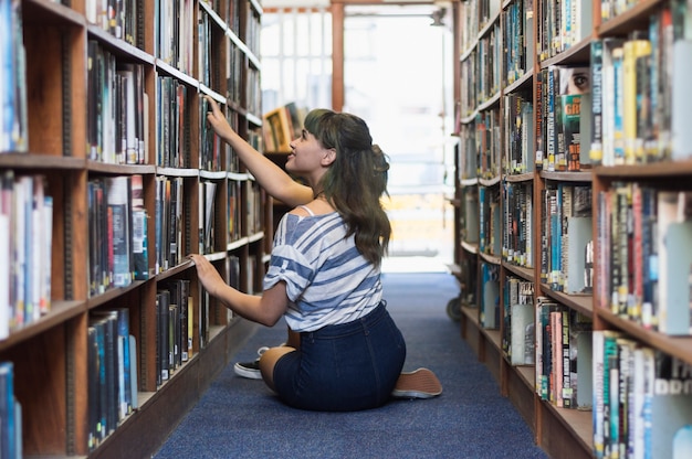 Meisje op zoek naar boek in een bibliotheek