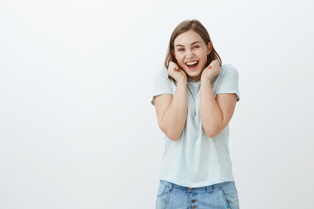 Meisje opgewonden bezoekende concert voor de eerste keer. charmante gefascineerde en gelukkige jonge vrouw in trendy t-shirt schreeuwen van vreugde en opwinding hand in hand in de buurt van gezicht reageren op geweldig nieuws