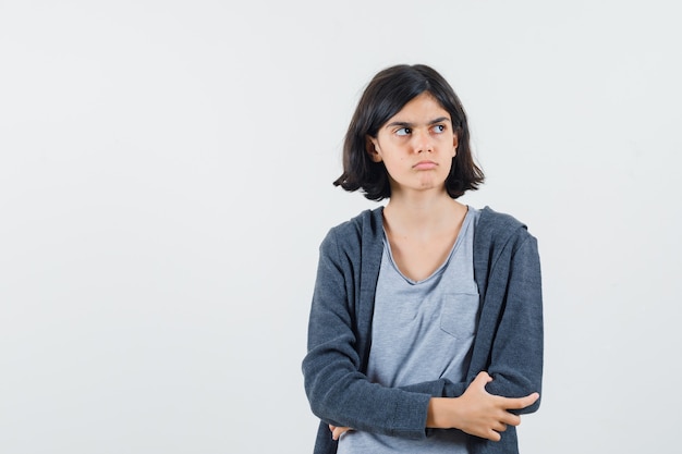 Meisje opzij kijken in t-shirt, jasje en peinzend kijken.